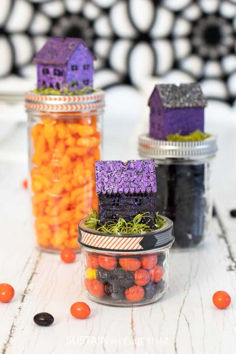 Candy filled mason jars with Halloween jar topper houses.