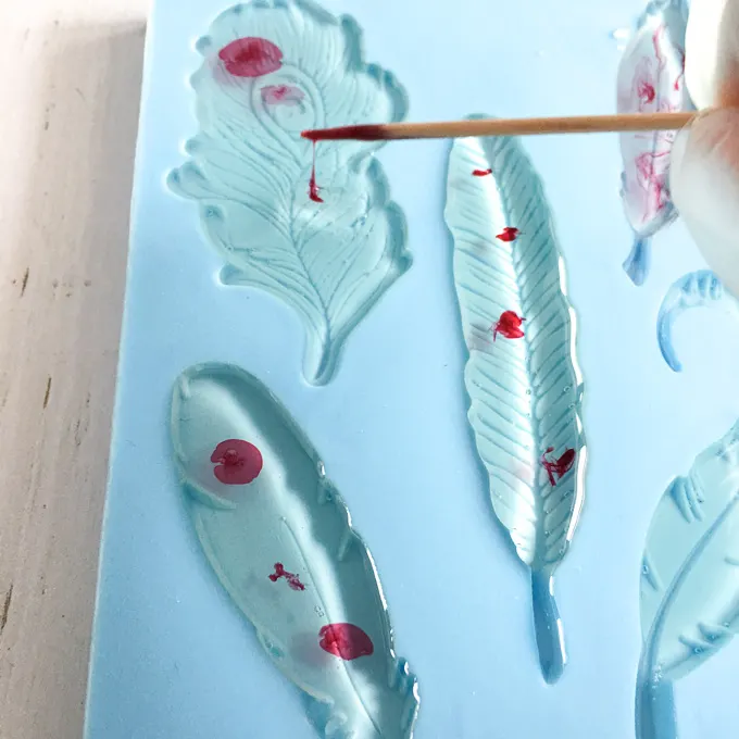Adding drops of dye into the resin in the feather molds.