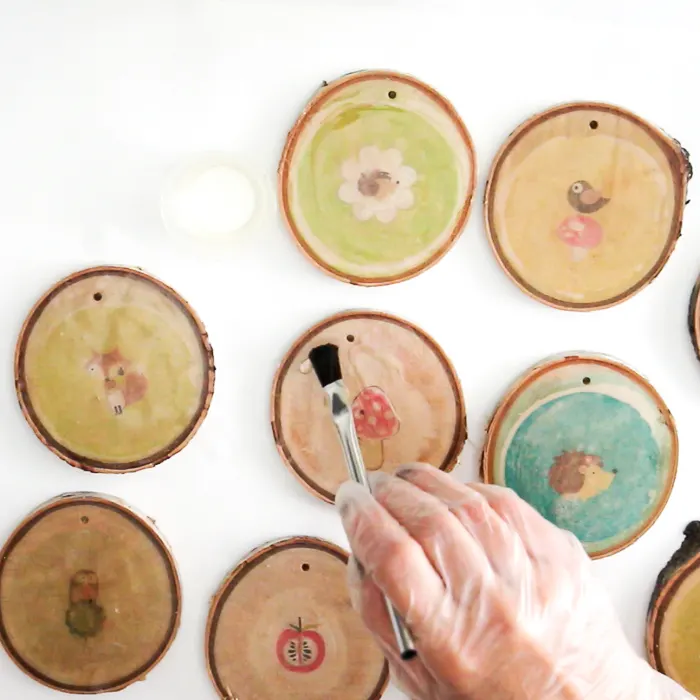 Using a paintbrush to add drops of resin to the wood slices.
