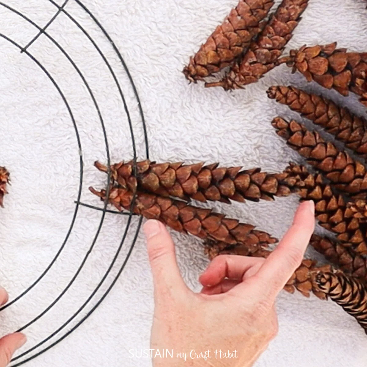 Inserting two pinecones onto the outside of the wreath wires.