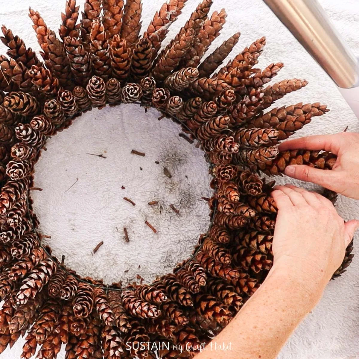 Adding the last pinecone to the wreath.