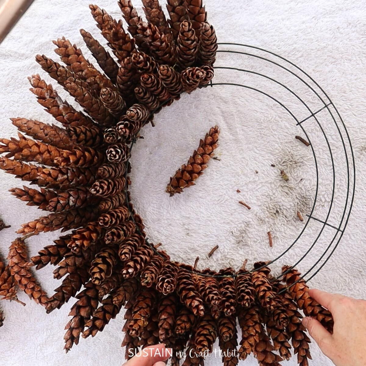 Continuing to make a pinecone wreath.