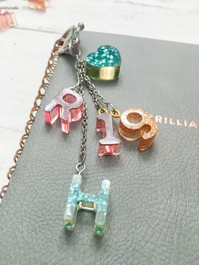 Monogram charms with resin attached to a notebook.