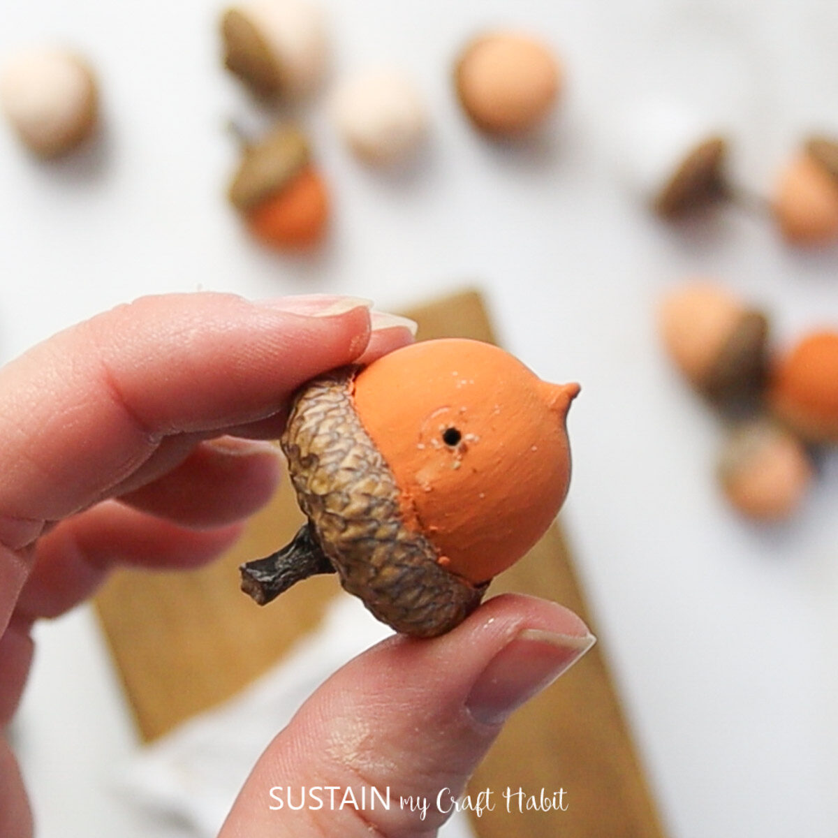 Drilling a small hole in the painted acorns.