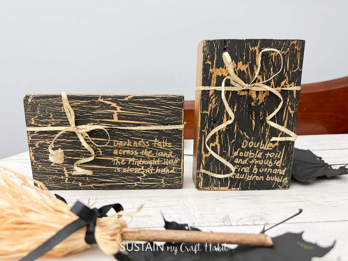 Two wood blocks with a black crackle paint finish and gold embellishments.