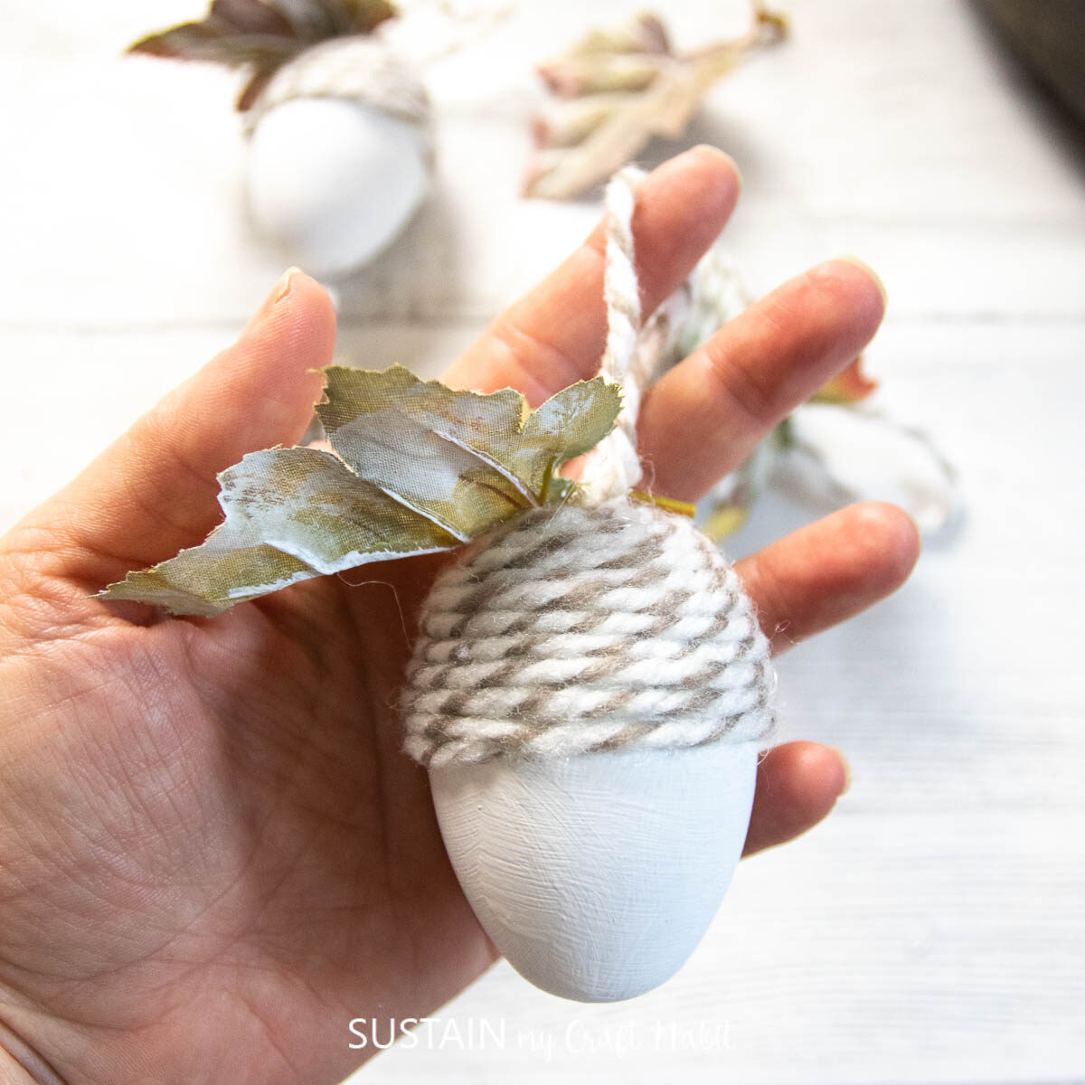 Hand holding an upcycled plastic egg acorn ornament craft.