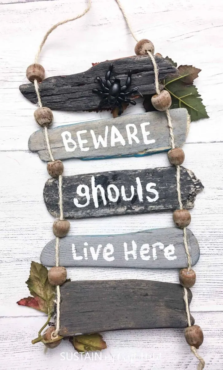 Reversible driftwood wall decor for fall with "beware ghouls live here" on the front with a faux spider.