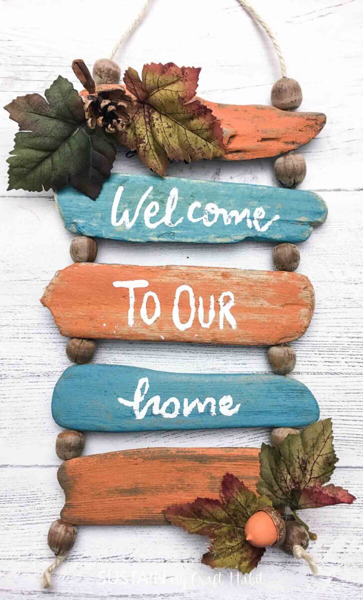 Reversible driftwood wall decor for fall with "welcome to our home" on the front with faux leaves. 