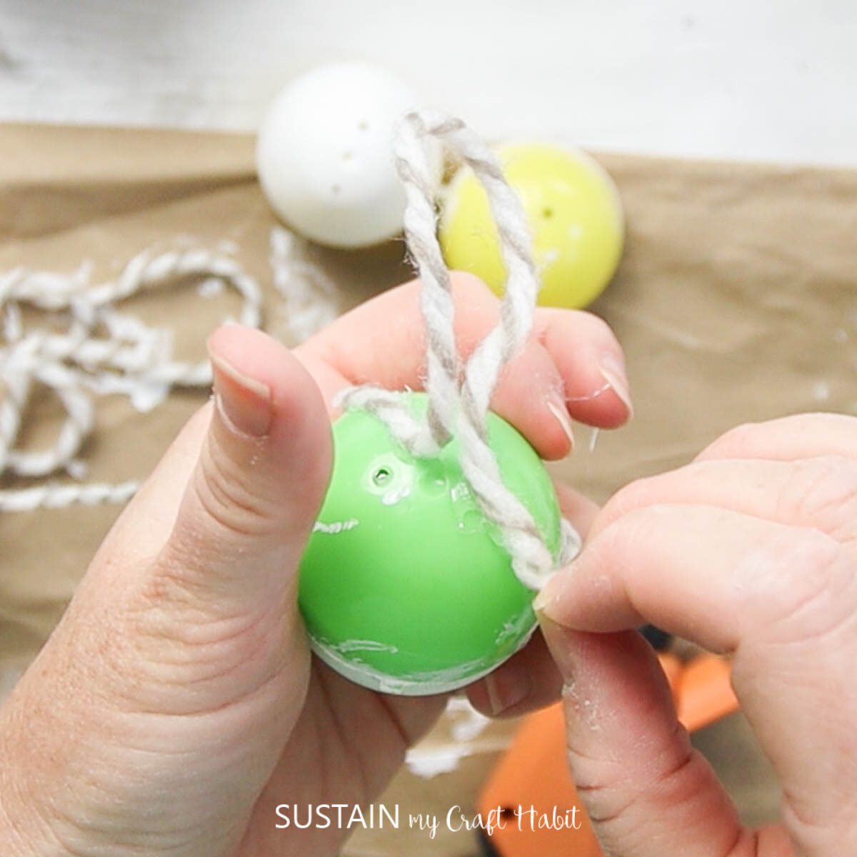 Gluing yarn onto a plastic egg.