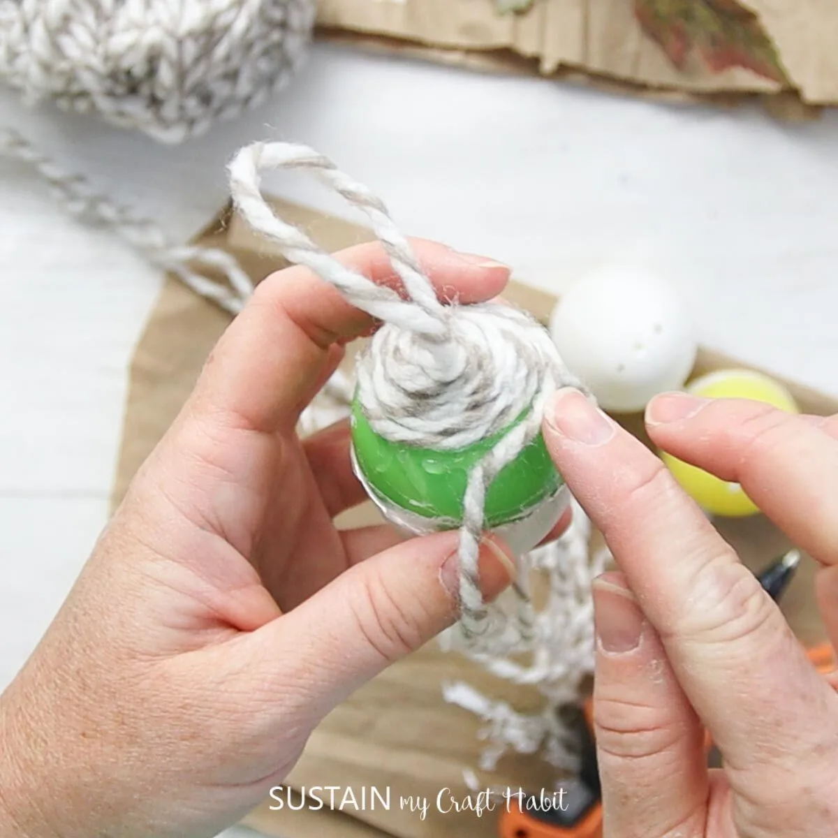 Gluing yarn around the plastic egg.