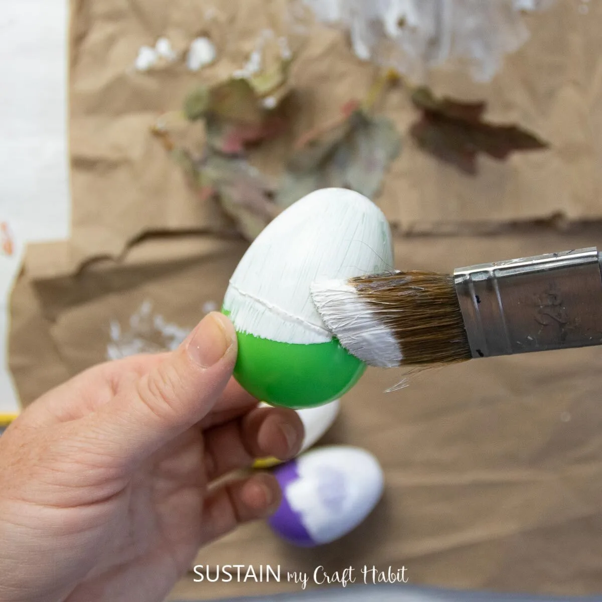 Painting a plastic egg with white paint.