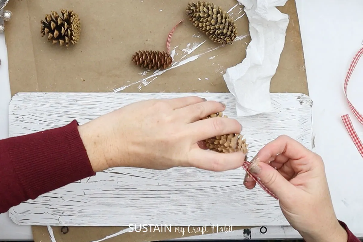 Attaching ribbon to a pine cone.