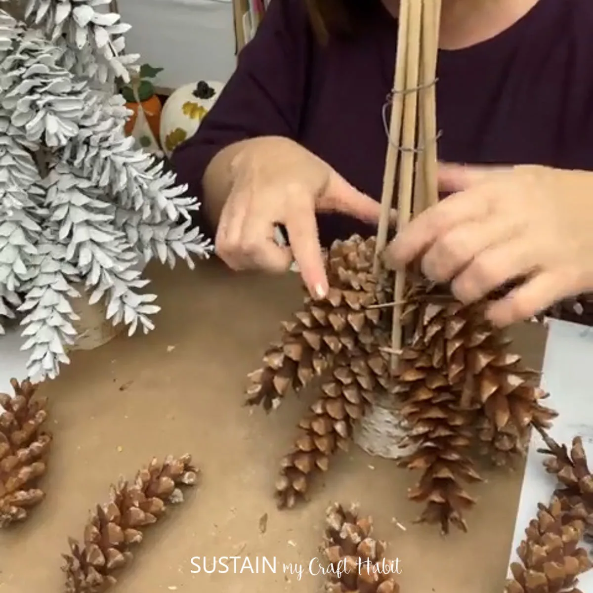 Attaching pine cones to the bottom of wooden dowels.