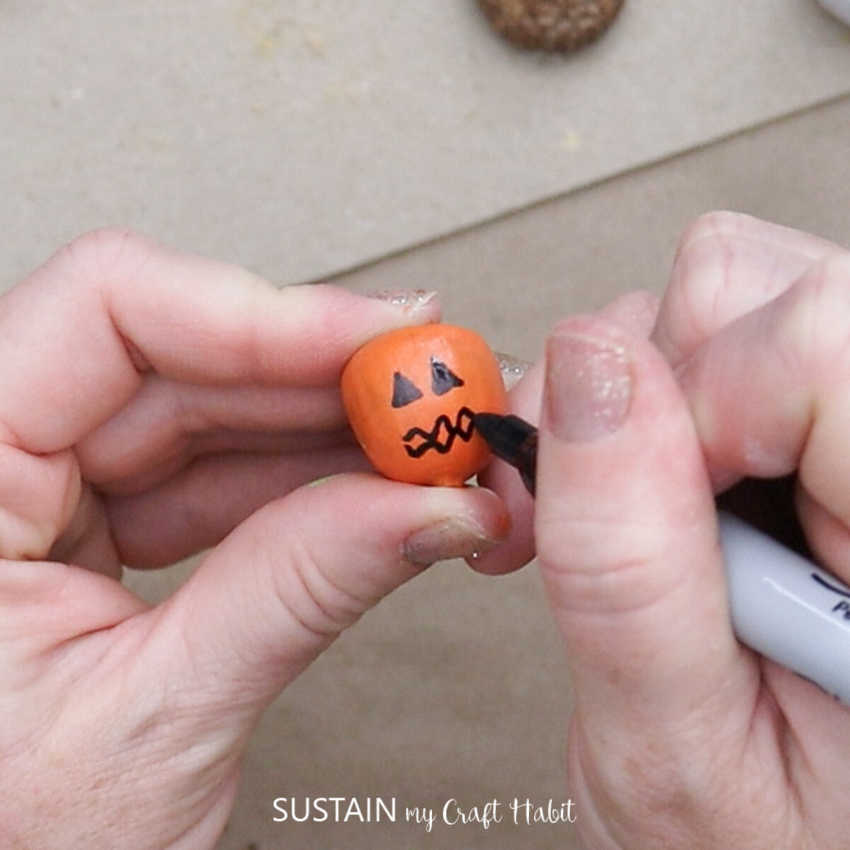 Adding a jack-o-lantern face to the painted acorn.
