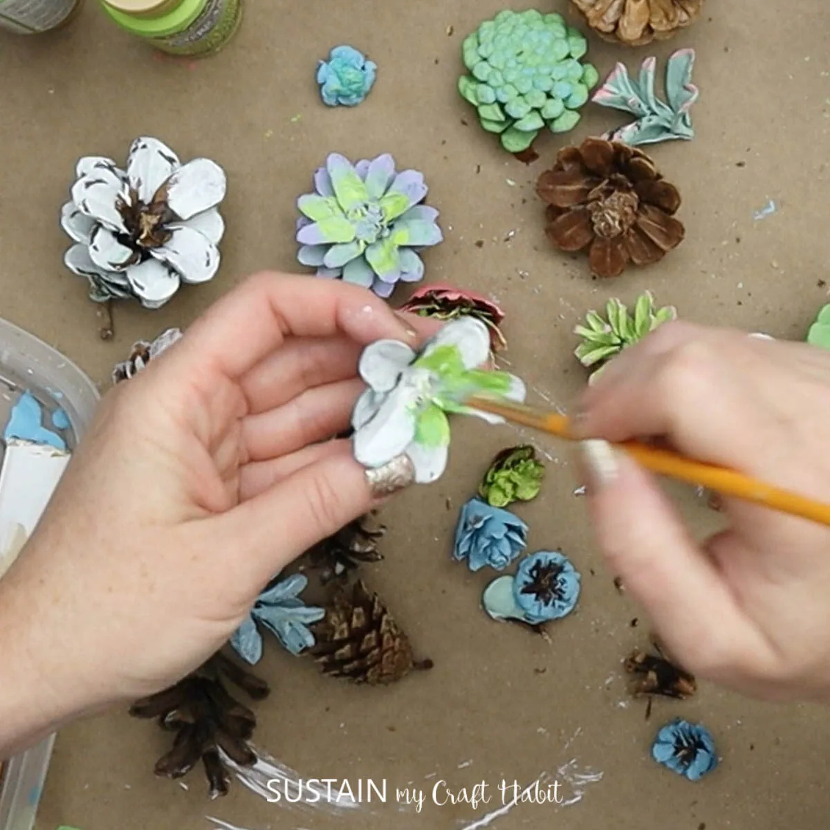 Painting a cut pine cone with green paint.