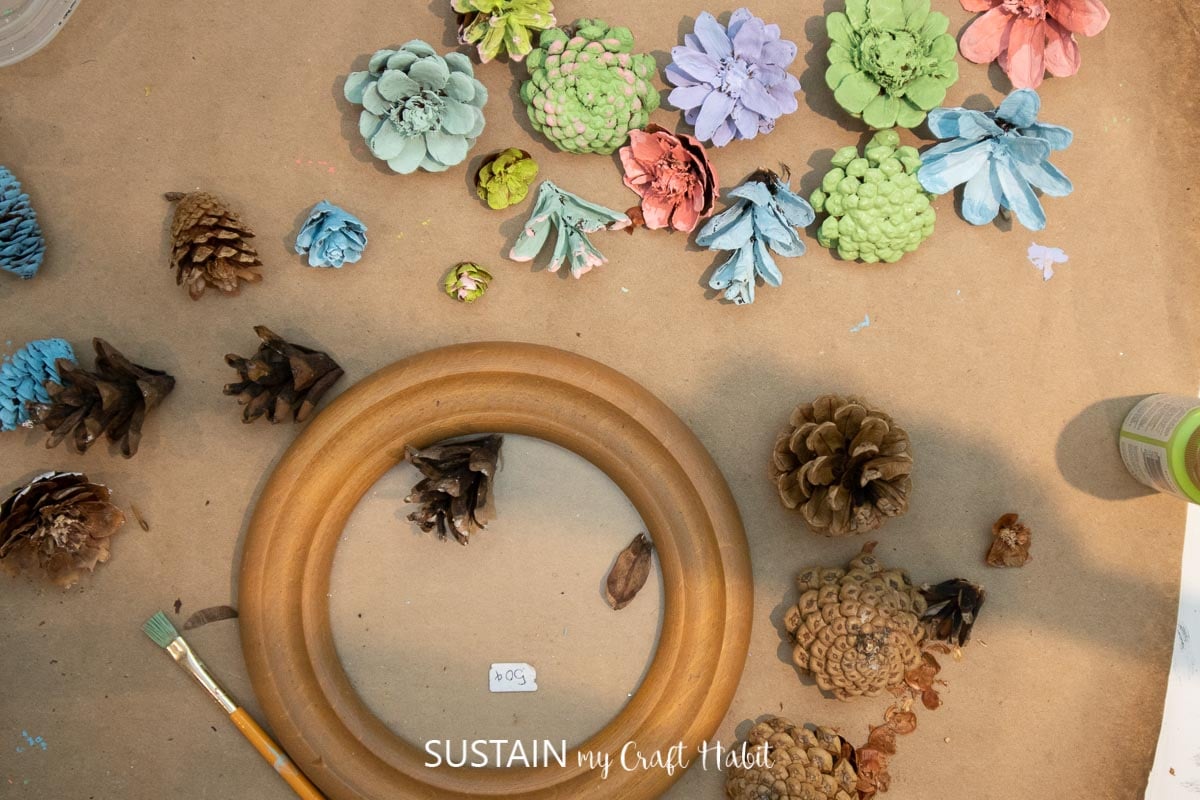 Materials needed to make pinecone succulents including a picture frame, pine cones, paint and paint brush.