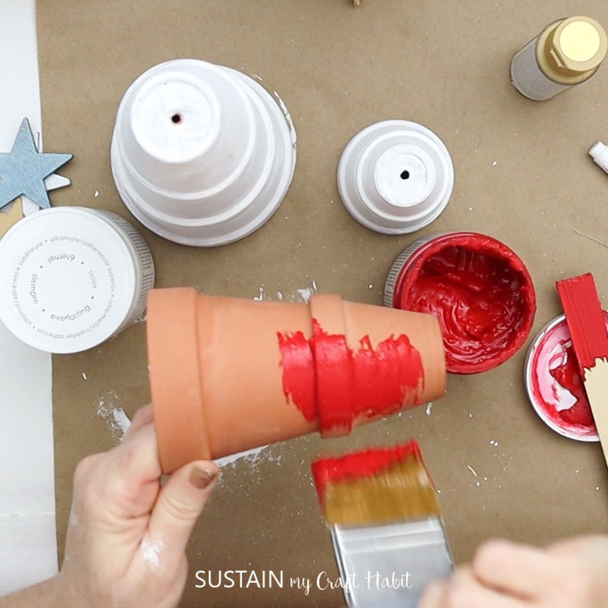 Painting the stacked terracotta pots red.