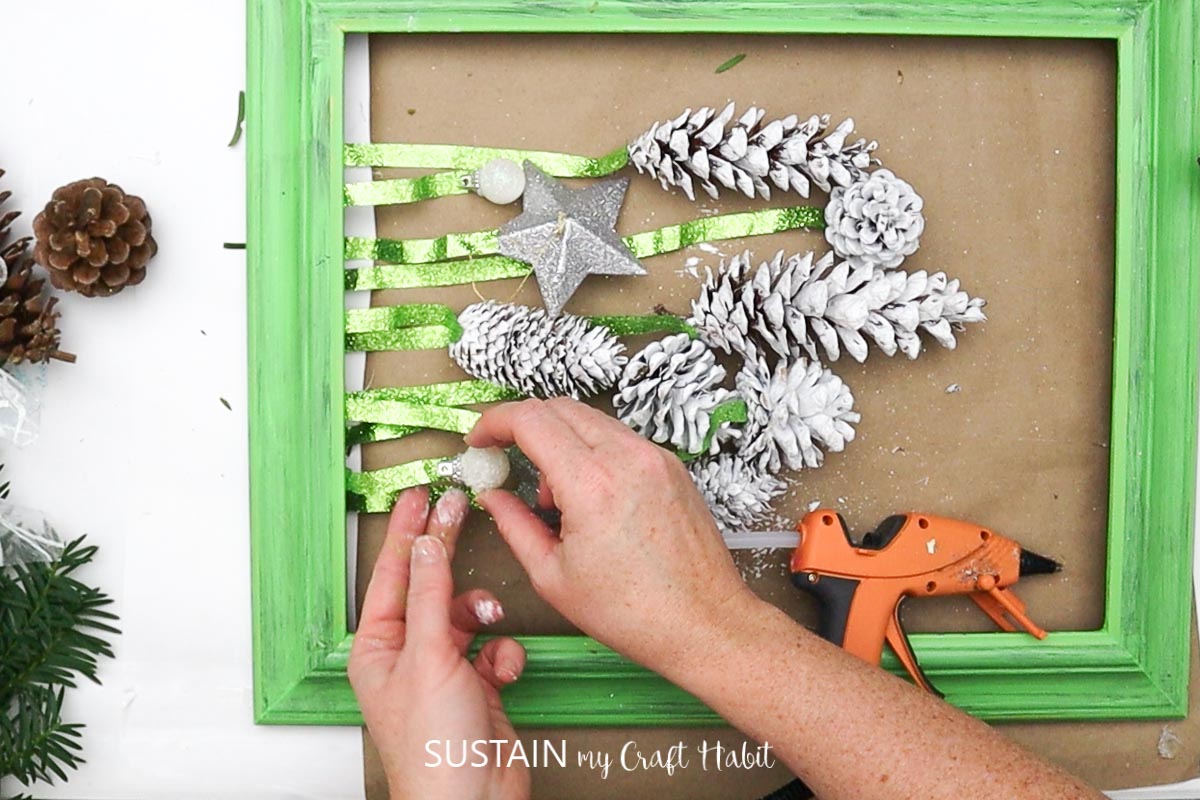 Attaching ornaments to green ribbon.