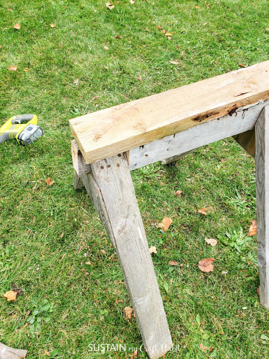 Adding a piece of wood on top of the wooden sawhorse.