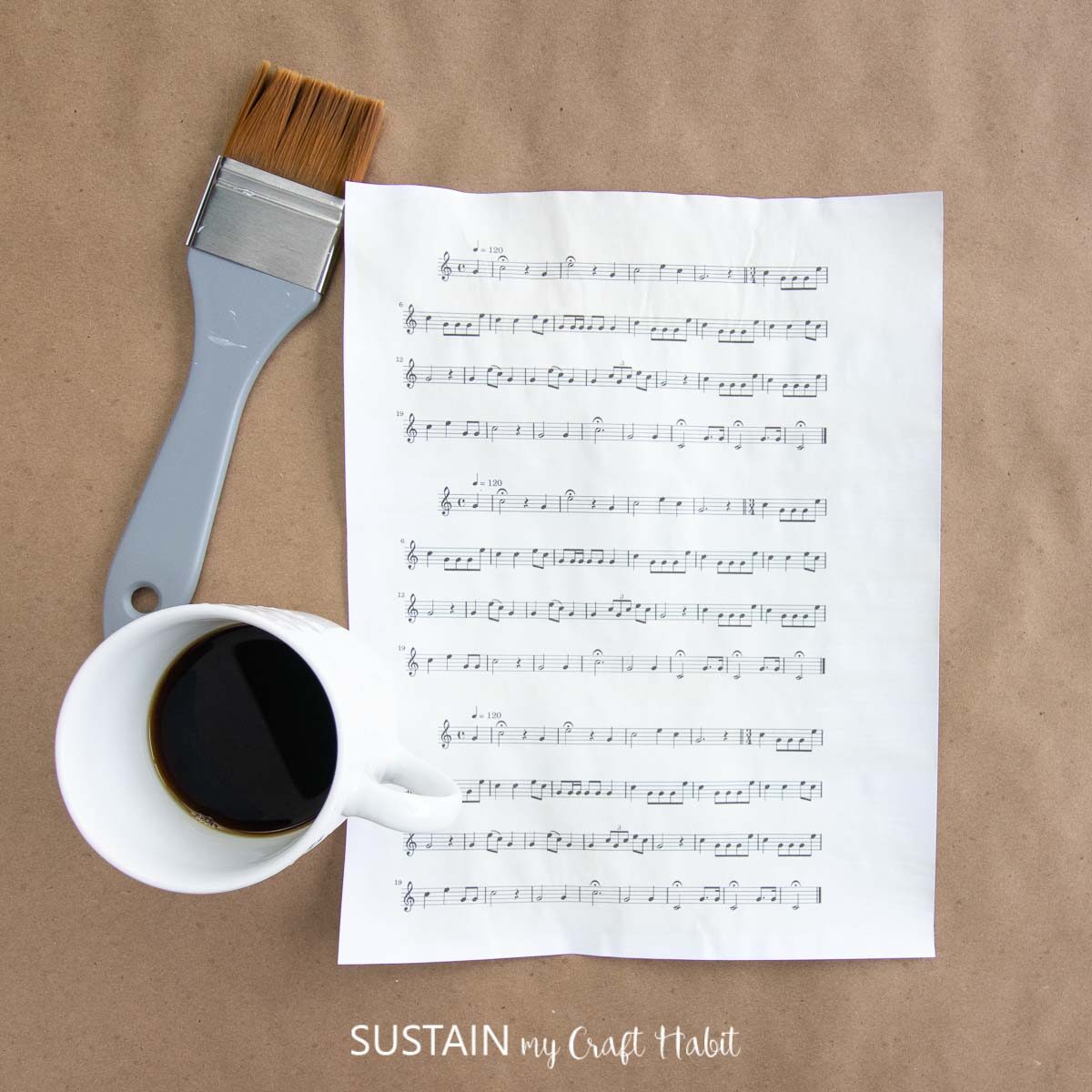 Music sheet next to a paint brush and a cup of coffee.