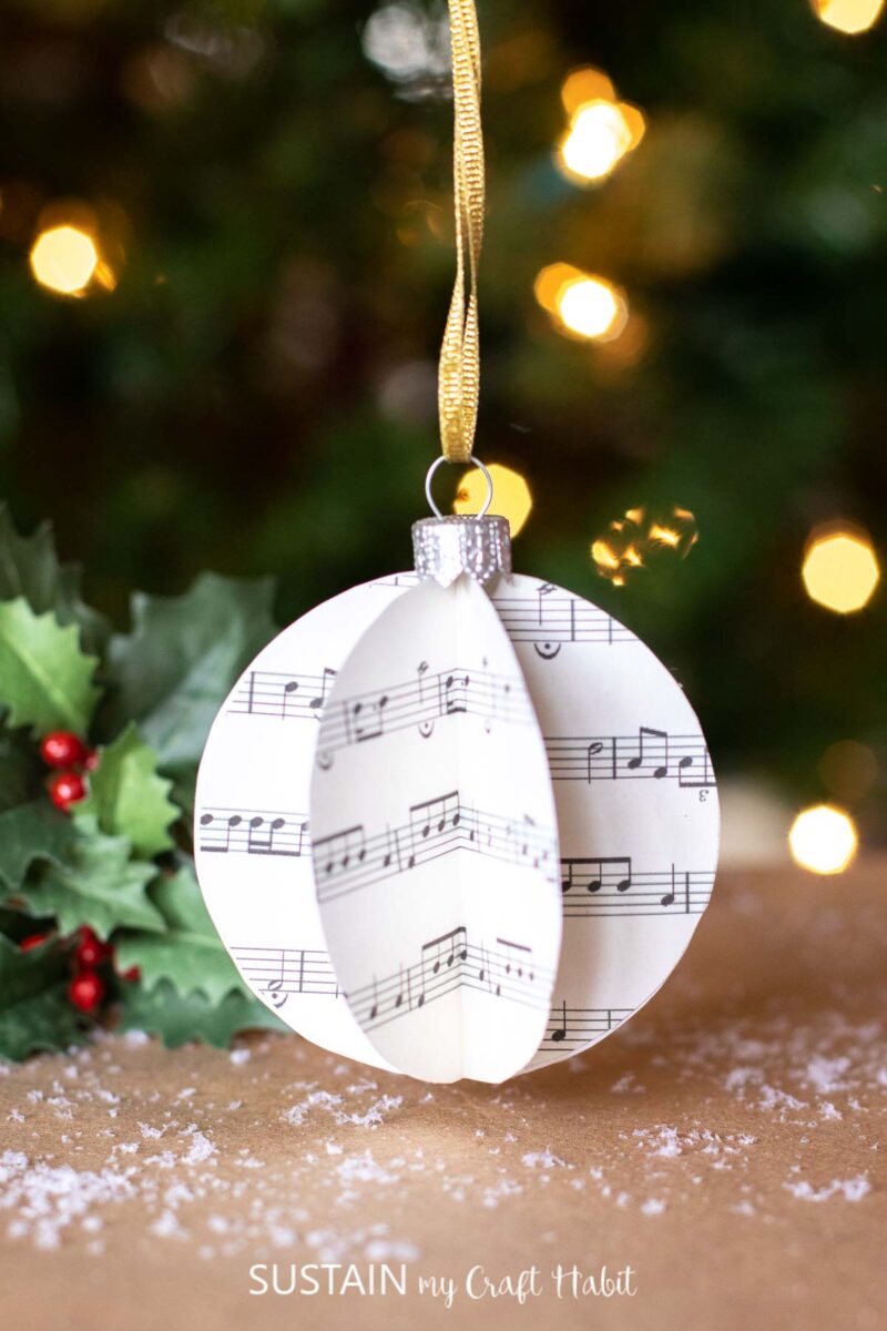 3D sheet music ornament hanging from a tree.