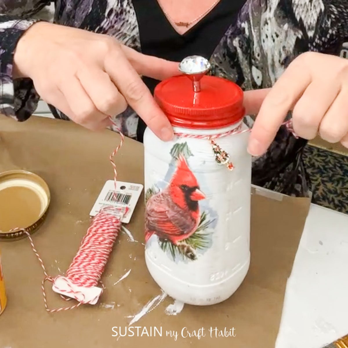 Wrapping ribbon around the mason jar to complete the Christmas decoupage idea.