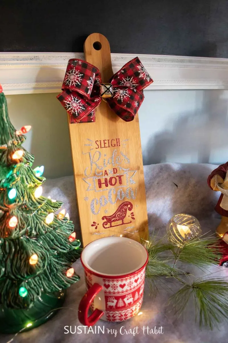 Hot cocoa bar sign leaning against a wall, next to Christmas decor and a mug.