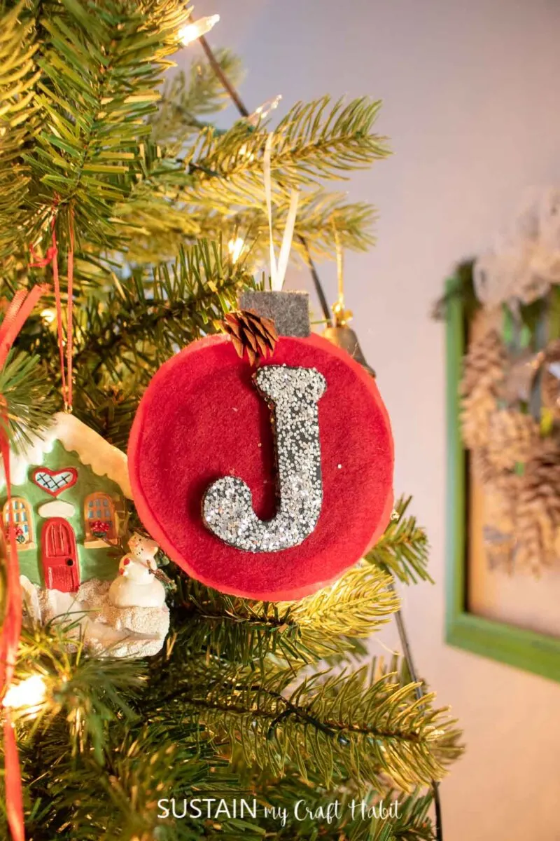 Felt monogram ornament hanging in a Christmas tree.