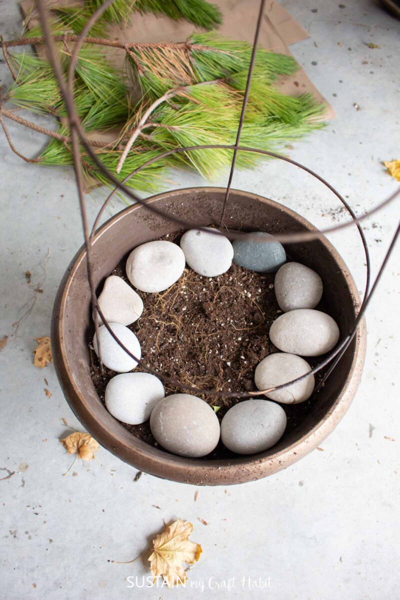 Adding rocks to the bottom of the planter pot.