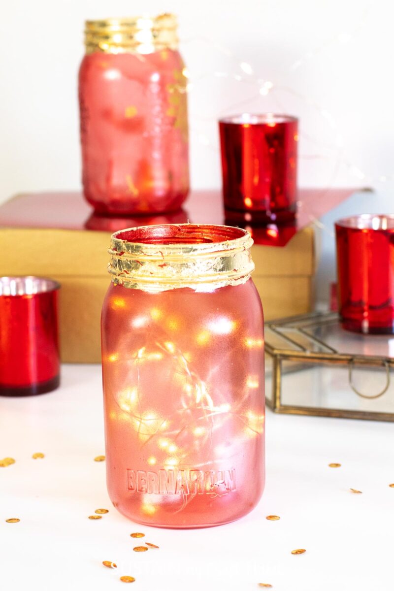 Chinese new year mason jar decor idea with twinkle lights next to red candle holders.
