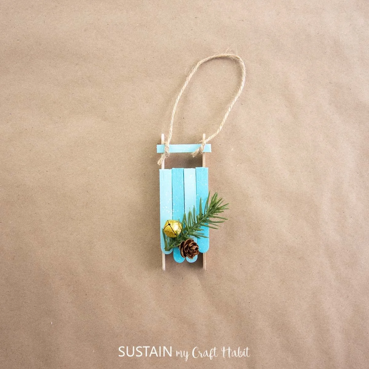 Popsicle stick sled ornament with greenery embellishments and twine. 