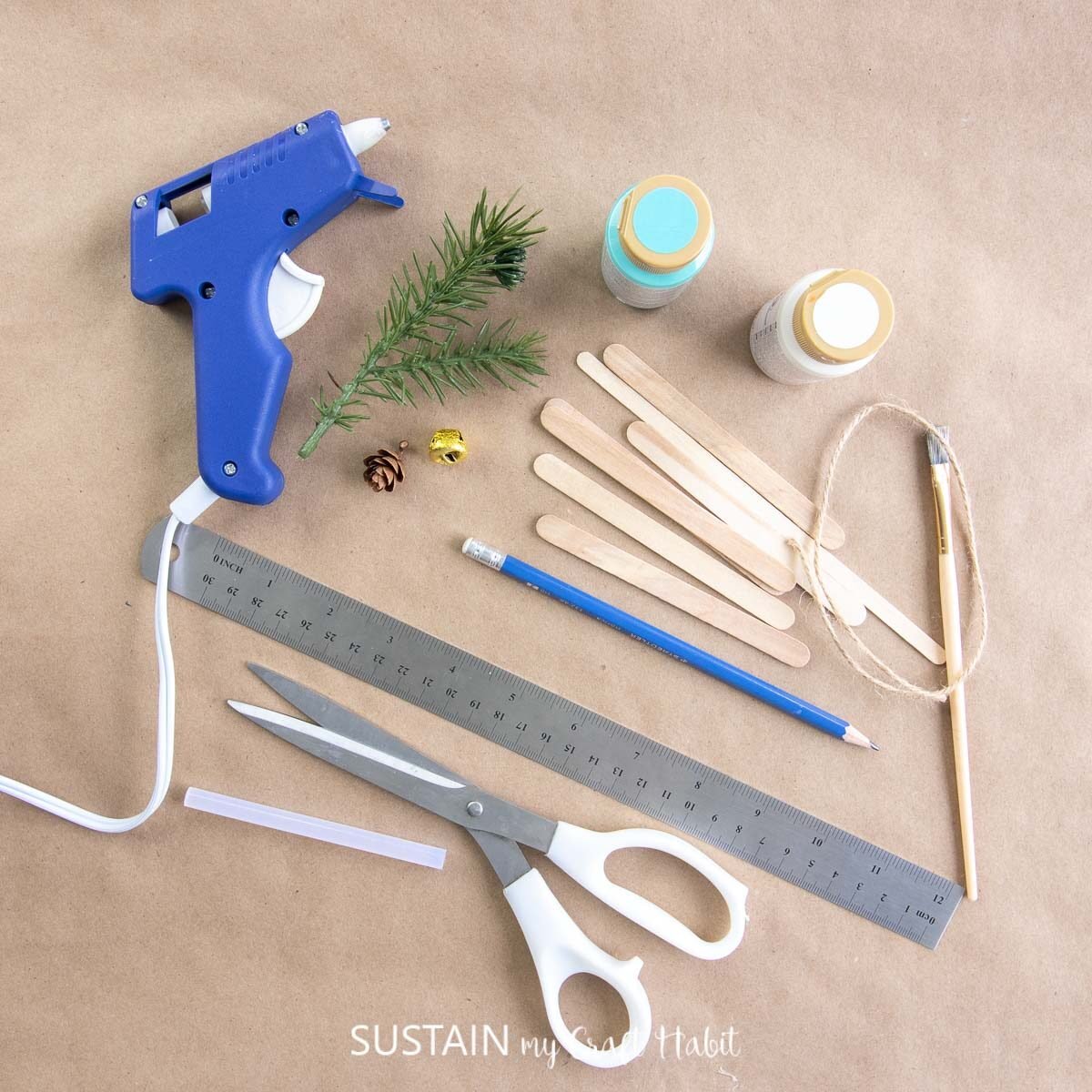 Materials needed to make a popsicle stick sled ornament including popsicle sticks, ruler, scissors, hot glue, paint and paint brush.