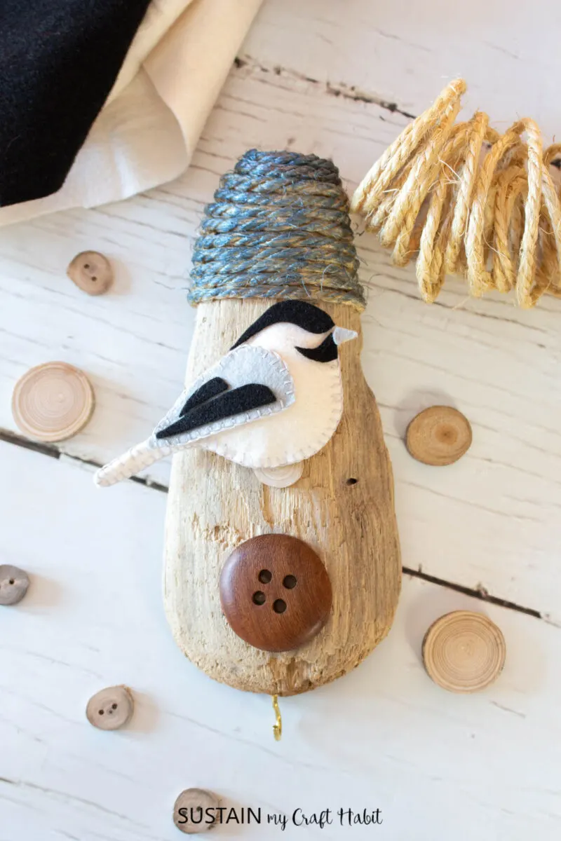 Birdhouse art craft with driftwood, rope, wood button and a felt bird.