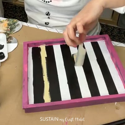 Peeling tape to reveal painted stripes.