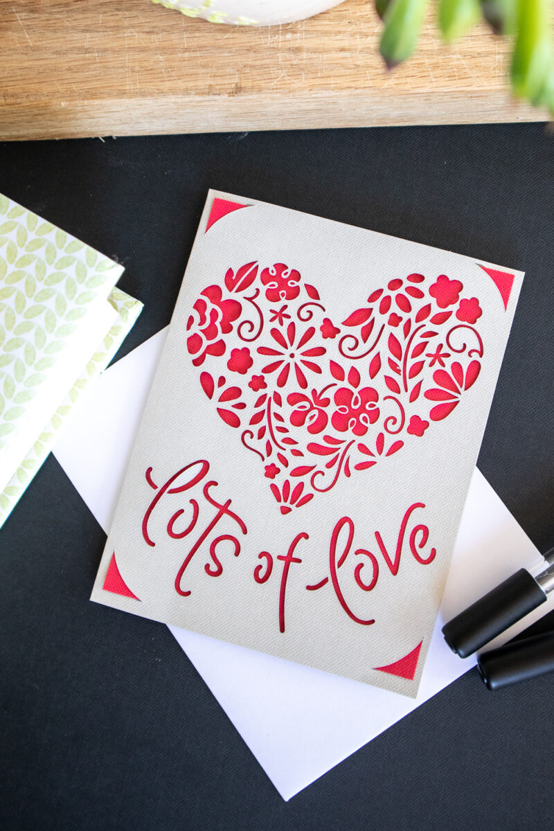 Handmade Valentine's day card with heart cut out and lots of love on the front.