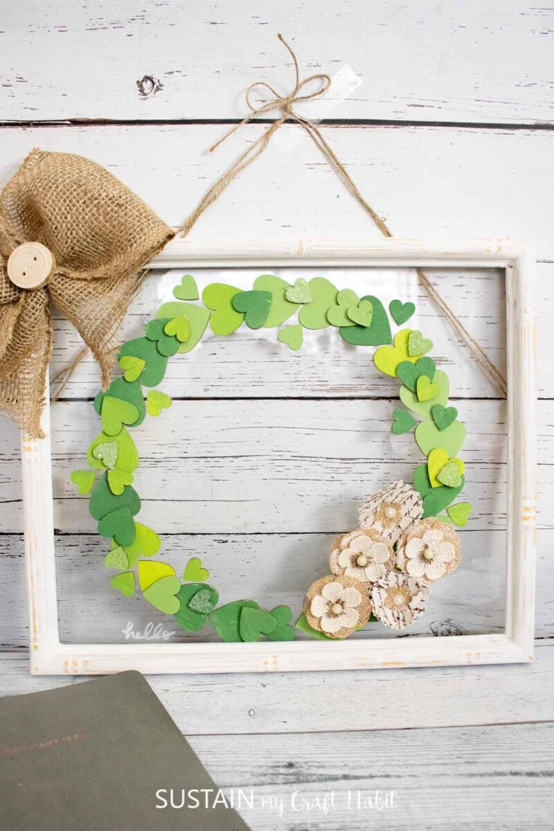 Wood heart cutout wreath in an upcycled picture frame with faux flowers and a burlap bow.