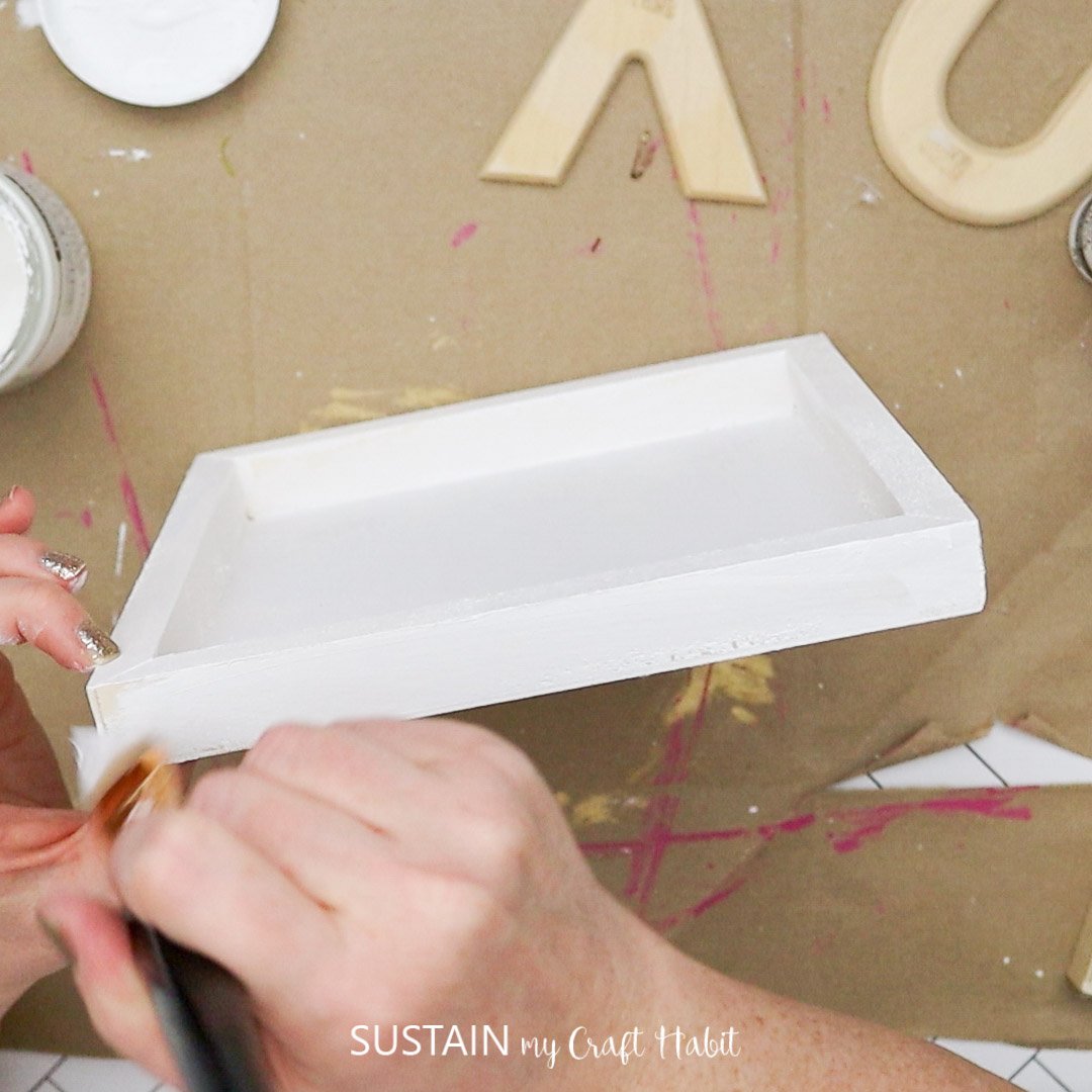 Painting a wooden plaque white.