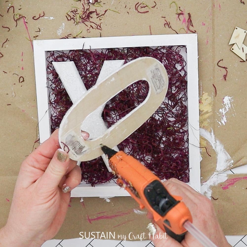 Adding hot glue to the back of a wood letter.