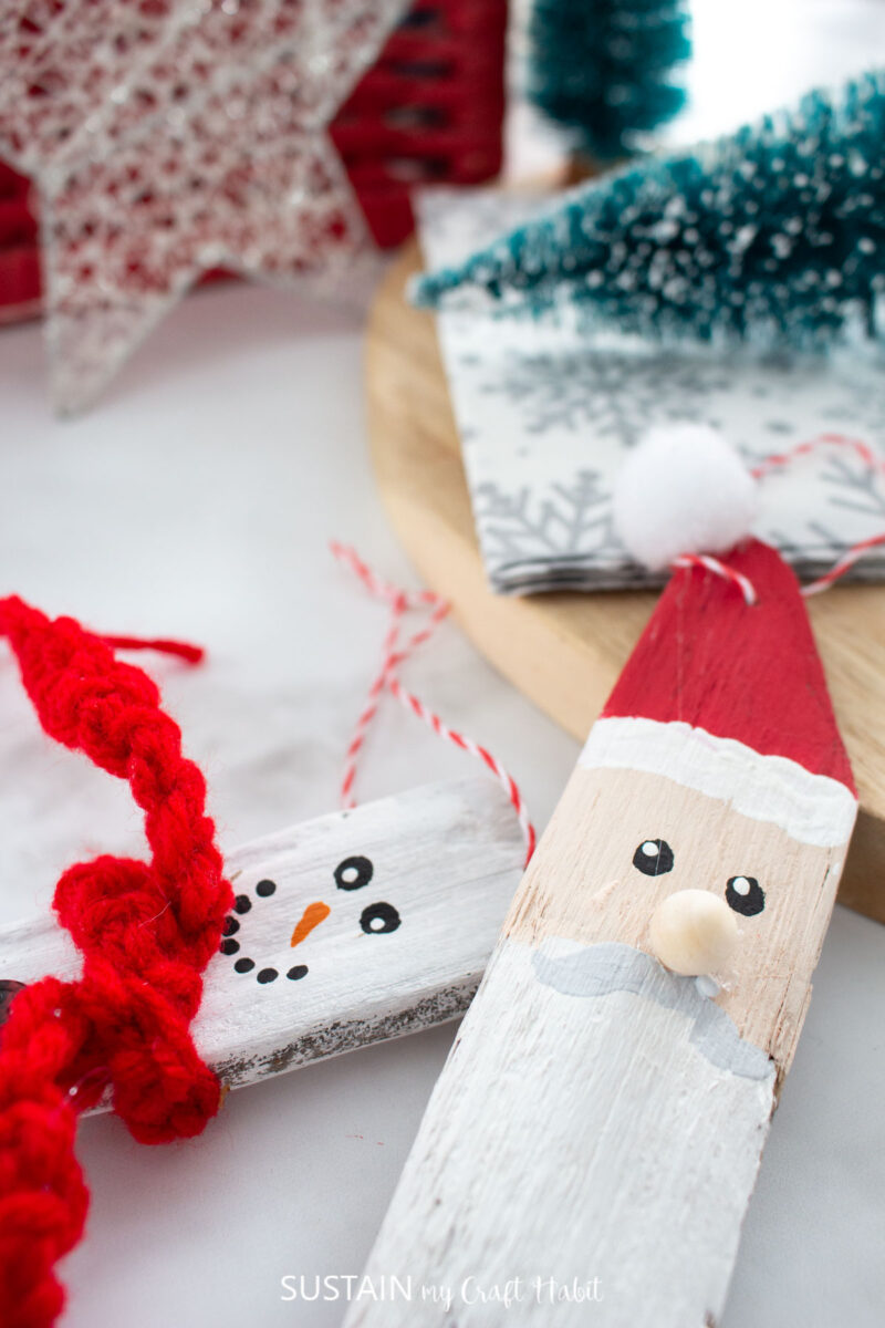 Close up a painted driftwood Santa next to a driftwood snowman.
