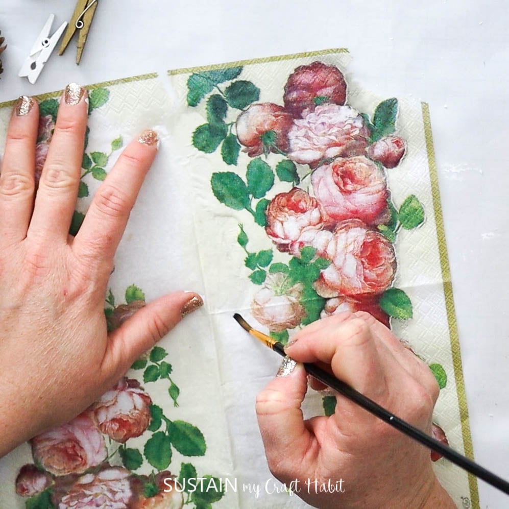 Using a wet paint brush to separate layers of a flower napkin.