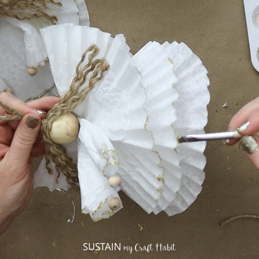 Painting the edges of the coffee filters with gold paint.