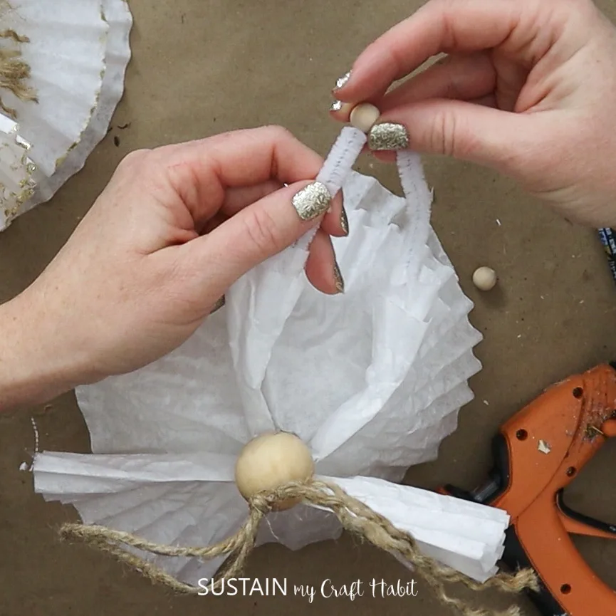 Attaching the coffee filter angel pipe cleaner arms with a small wood bead.