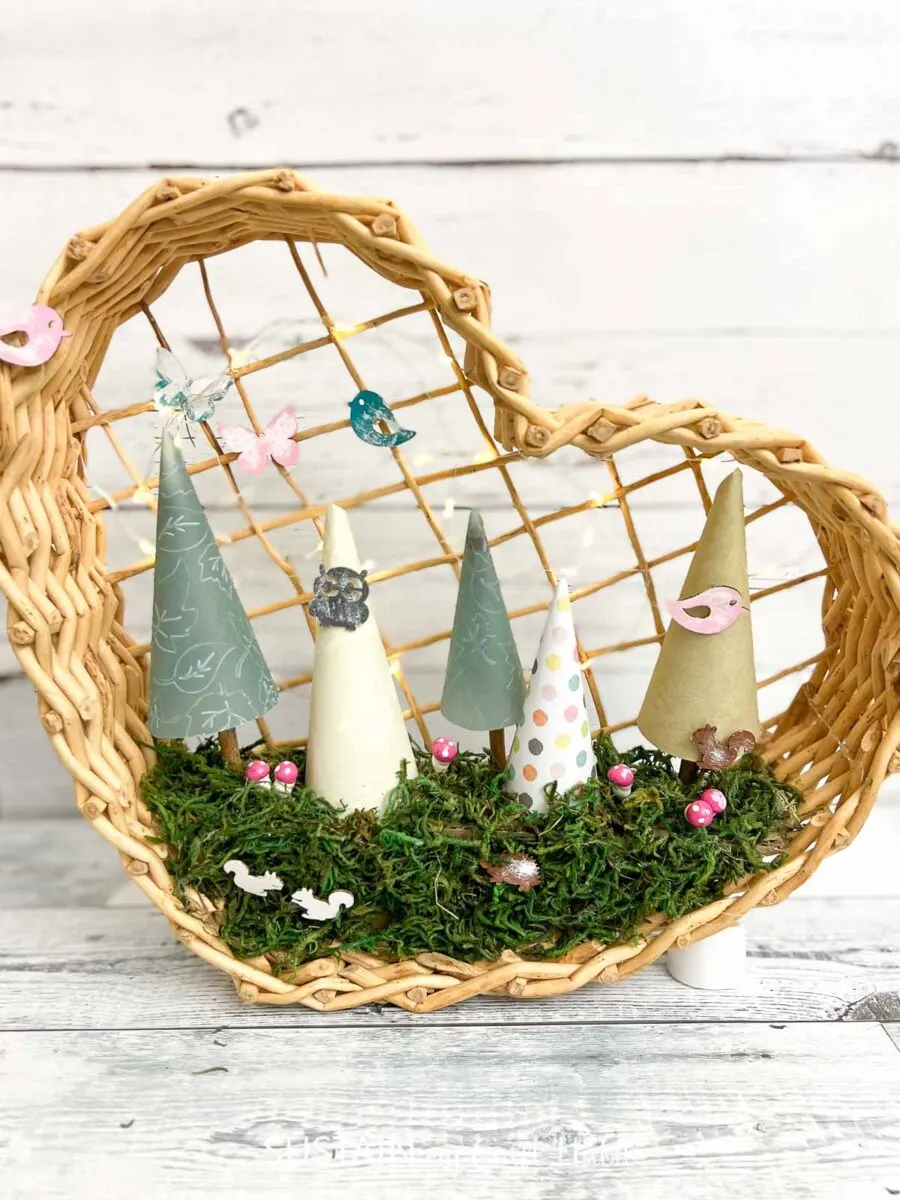 Whimsical paper fairy garden craft inside a heart shaped basket.