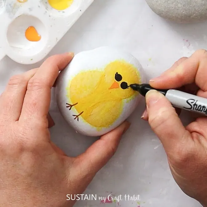 Using a sharpie marker to add eyes onto the baby chick.