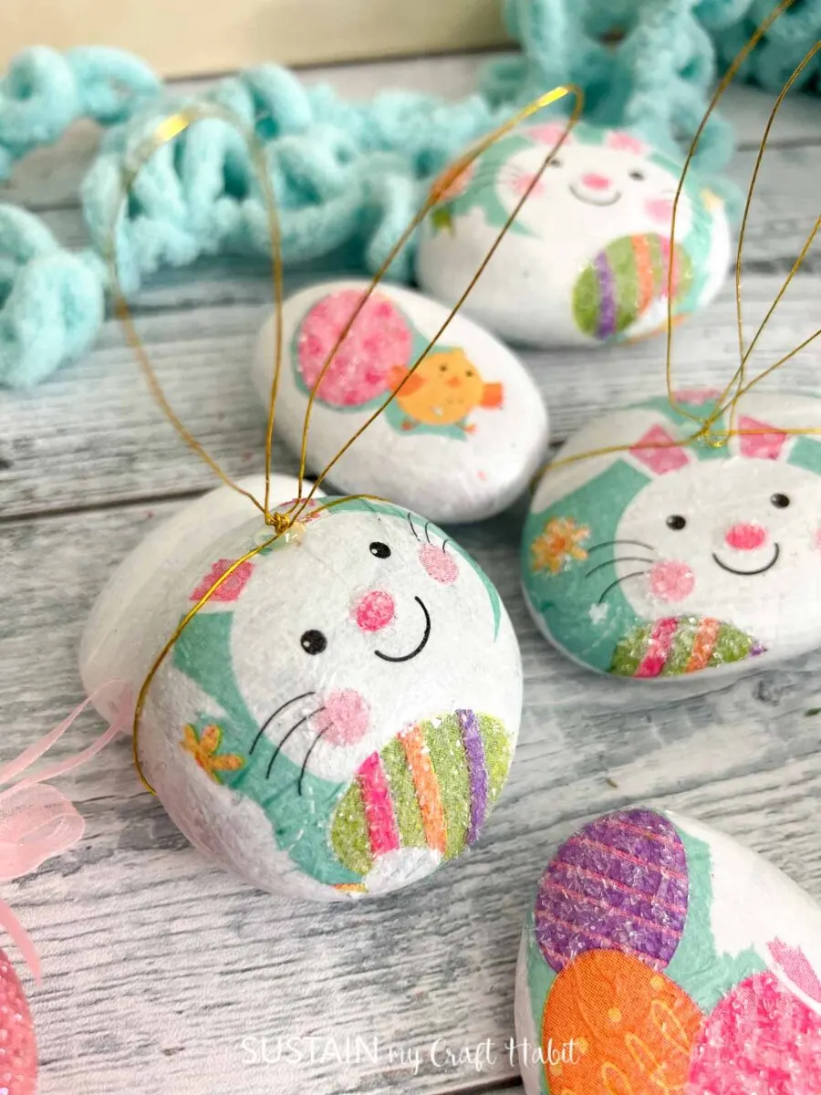 Decoupaged rock that look like Easter bunnies with wire ears.