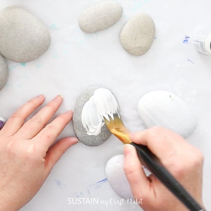 Painting rocks with white paint.
