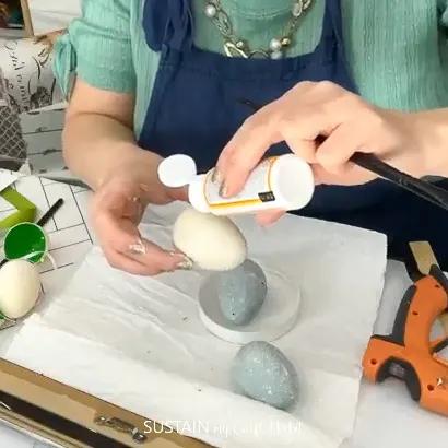 Adding mod podge to a painted plastic Easter egg.