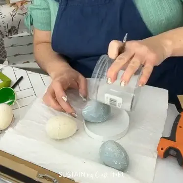 Adding diamond dust to a plastic Easter egg.