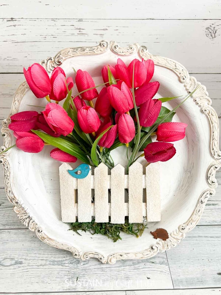 Upcycled silverware tray painted white and decorated with tulips, moss, white fence and bird cutout.