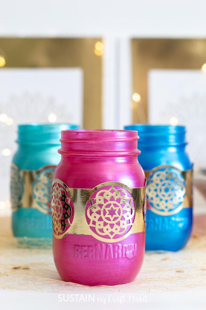 Diwali craft using painted glass jars and gold foil paper designs.